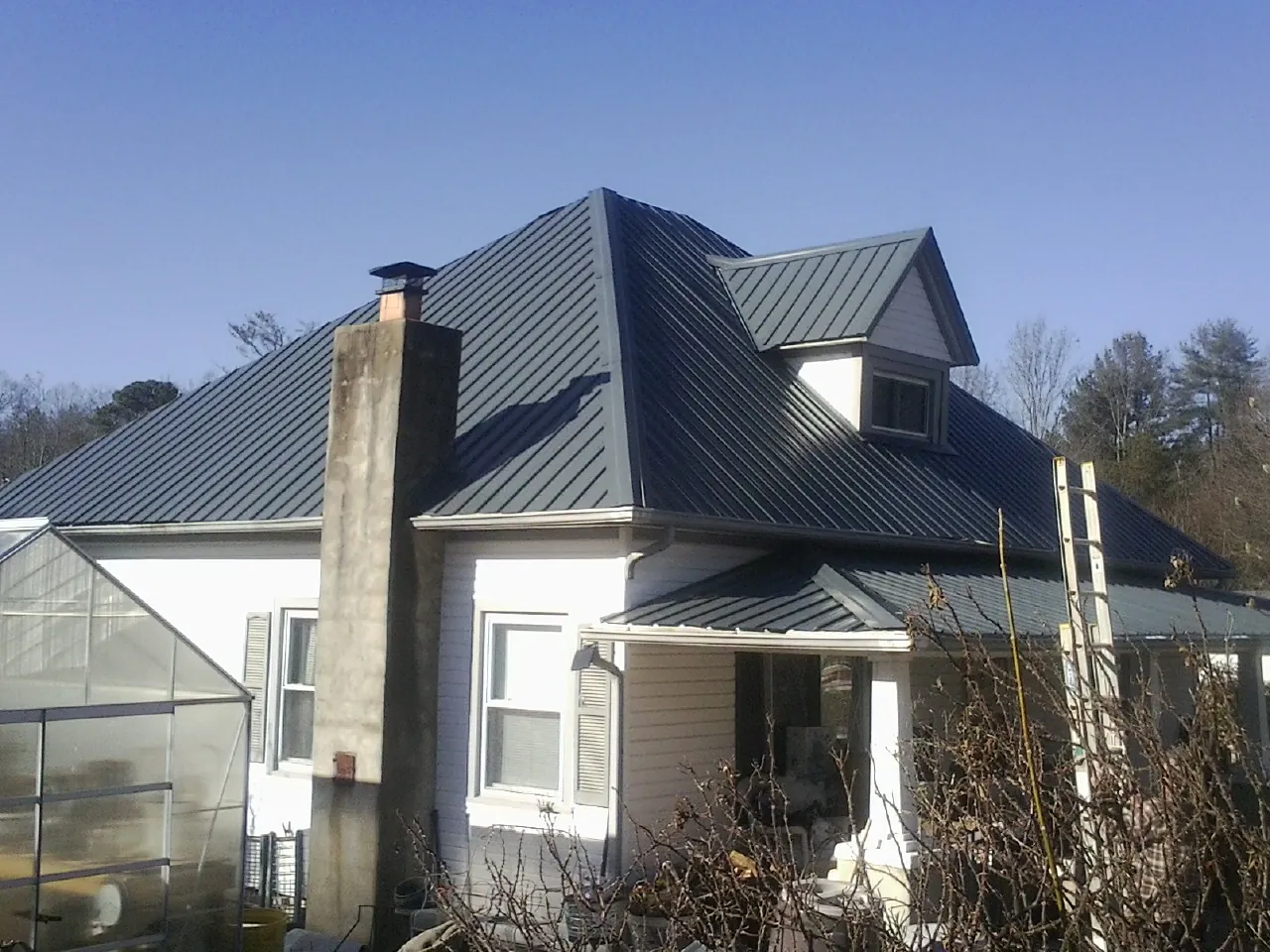 Dark blue standing seam metal roof on a white farmhouse with dormer — Slate & Tile Roof Repair by Roofing Brothers in Mesa