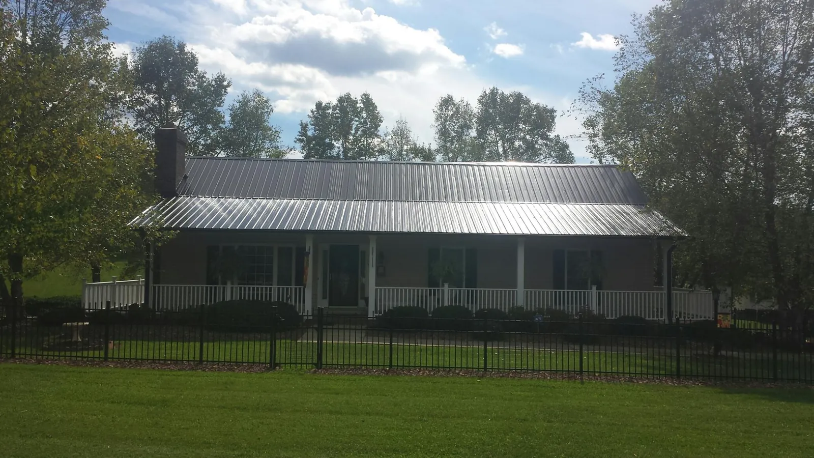 Gray metal roof on a brick ranch with a full width front porch — Gutter Guard Installation work by our crew in Mesa