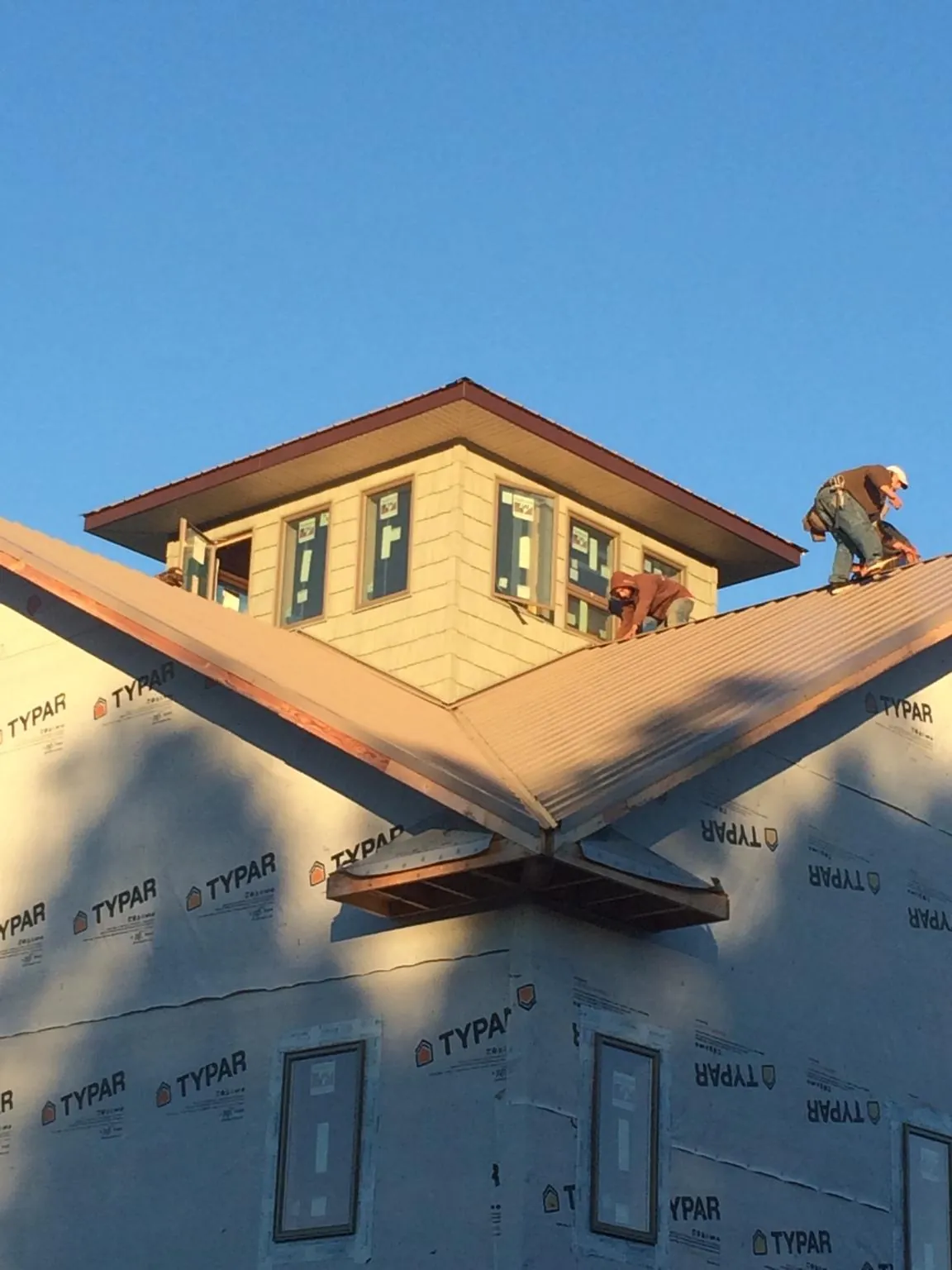 Roofers working around a rooftop cupola on a new metal roof at sunset — Roof Waterproofing in Mesa by Roofing Brothers
